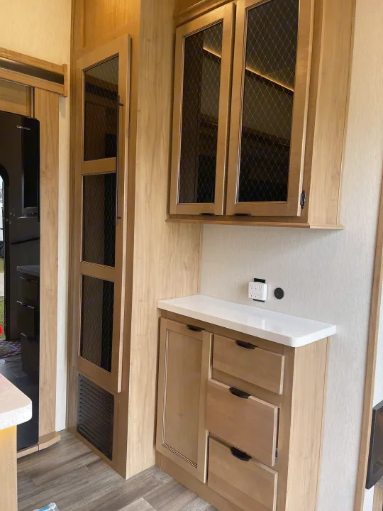 Inside a modern RV rental: light wood cabinets with glass fronts, white countertop, and power outlets for convenience.. Forest River Sabre 2024