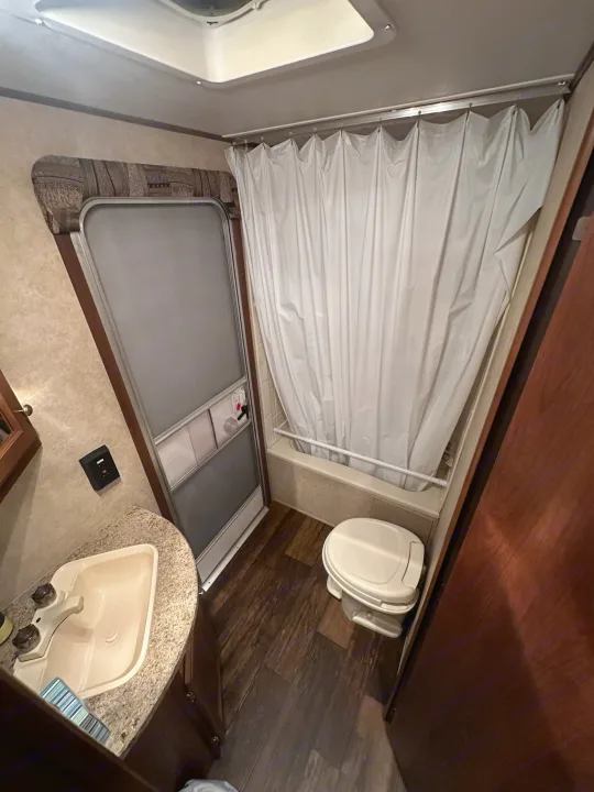 Inside an RV rental: a compact bathroom featuring a toilet, shower with curtain, and vanity sink with faucet.. Crossroads RV Z-1 2013