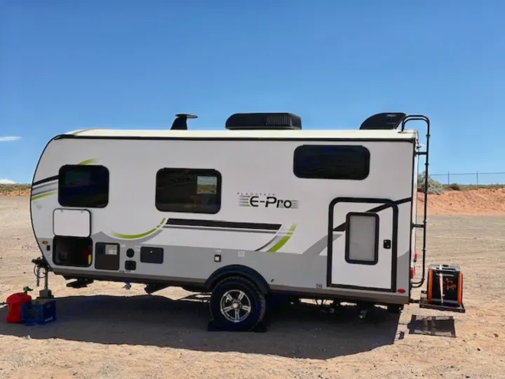 White Flagstaff E-Pro rv rental, a travel trailer, parked on dirt under a clear sky. Features AC & generator for camping.. Forest River Flagstaff E-Pro 2023