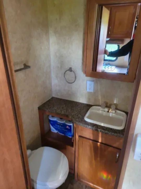 Clean RV rental bathroom with toilet, sink, mirror, and storage for essentials. Compact design.. Starcraft Autumn Ridge 2011