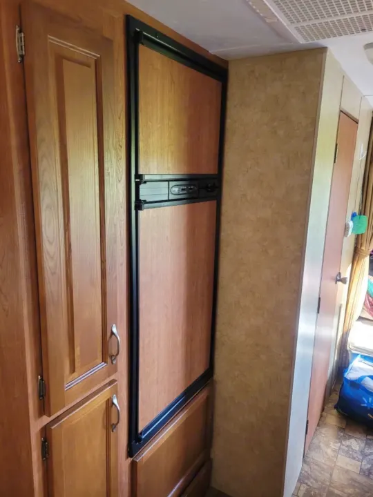 An RV rental's interior features built-in wood cabinetry and a fridge, showcasing a compact and practical living space.. Starcraft Autumn Ridge 2011