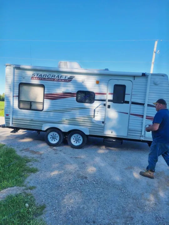 STARCRAFT Autumn Ridge travel trailer on gravel, a great RV rental option. A man walks beside the unit.. Starcraft Autumn Ridge 2011