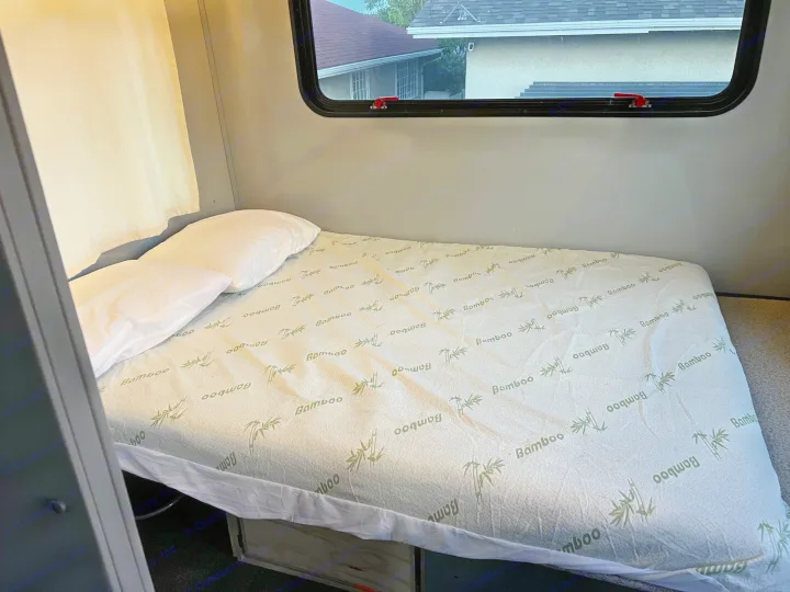 Comfortable RV rental bed with a bamboo mattress cover and window view, ready for travel adventures.. Chevrolet Express shuttle 2014