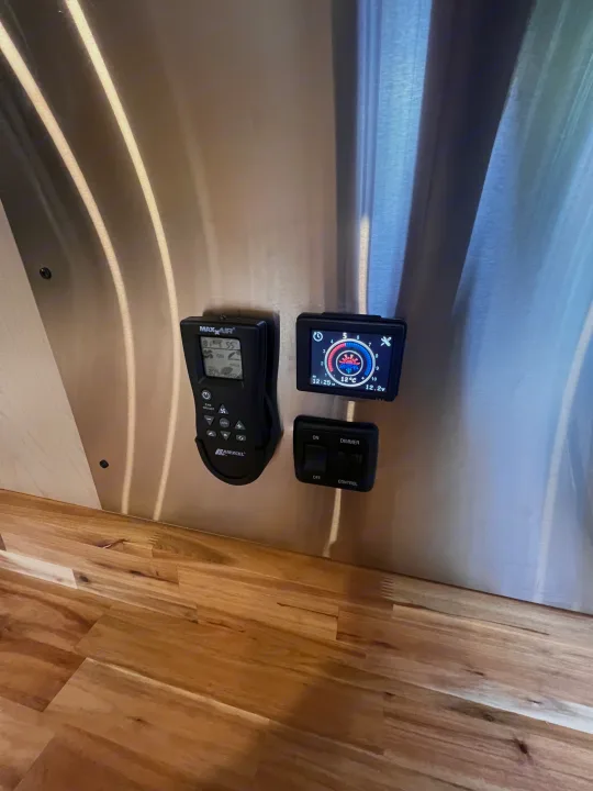 RV rental interior featuring climate control, fan (Maxxair), and light dimmer panels on a metal wall above wood flooring.. Mercedes Sprinter 2024