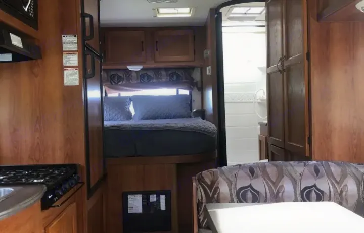 Interior of an RV rental: kitchen, elevated bed, bathroom, and dinette. A functional, compact space.. Coachman RV Freelander 2011