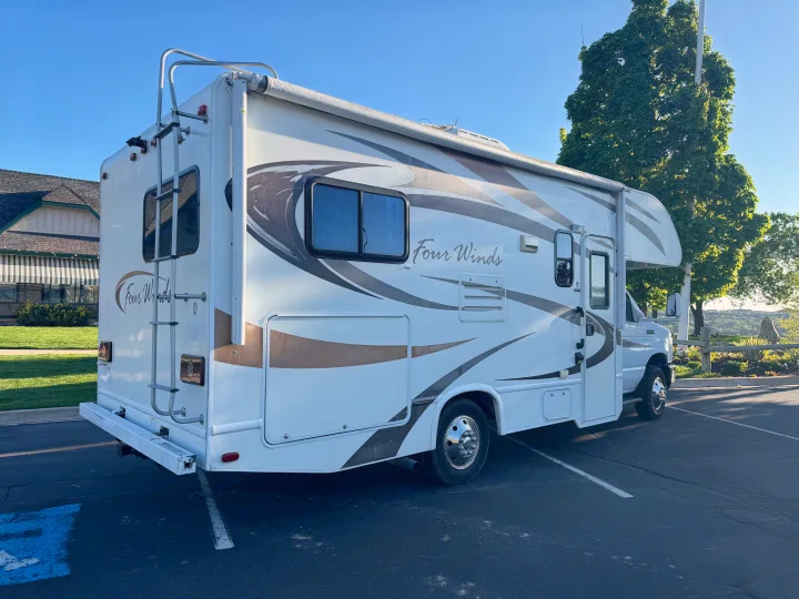 This white and brown Class C rv rental motorhome is parked on a sunny day, ready for travel adventures.. Thor Four Winds 2014