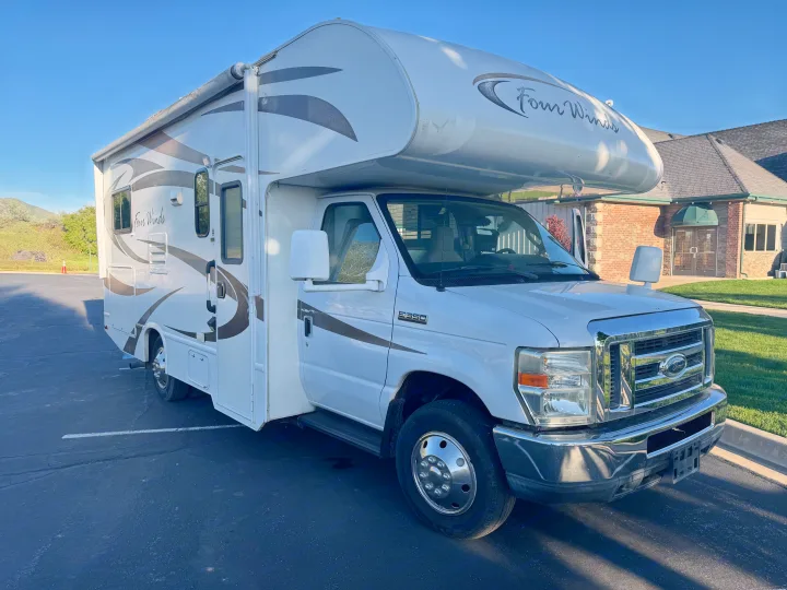 White Four Winds Class C RV rental, a motorhome on a Ford E-350 chassis, parked in a lot.. Thor Four Winds 2014