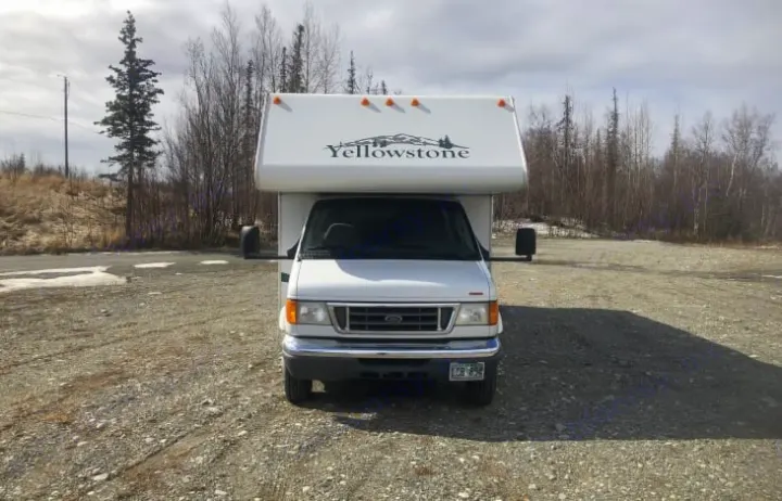 White Class C Yellowstone RV rental parked on a gravel lot, surrounded by bare trees. Ideal for your next outdoor road trip.. Gulf Stream RV 6237 2008