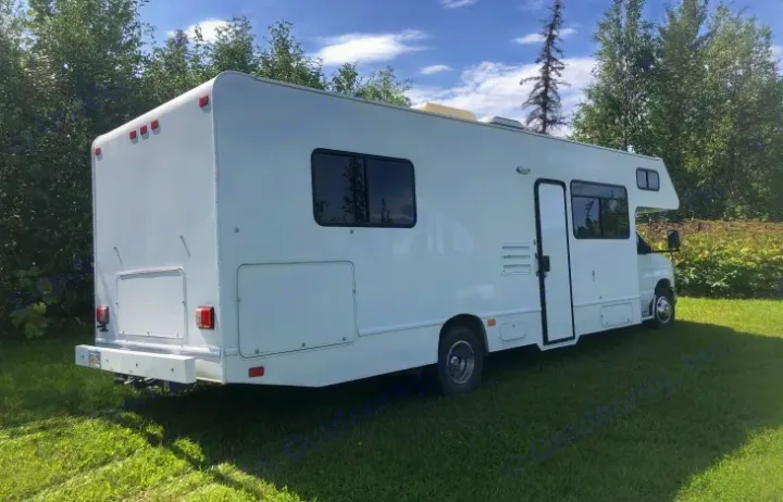 Clean white RV rental (motorhome) on green grass, shown from the rear-side view, ready for travel.. Thor Majestic 2016