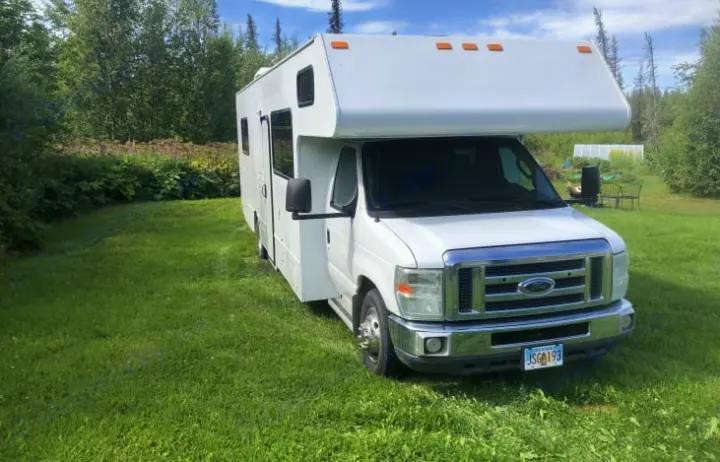 A white Class C rv rental is parked on vibrant green grass, surrounded by lush trees, ready for adventure.. Thor Majestic 2016