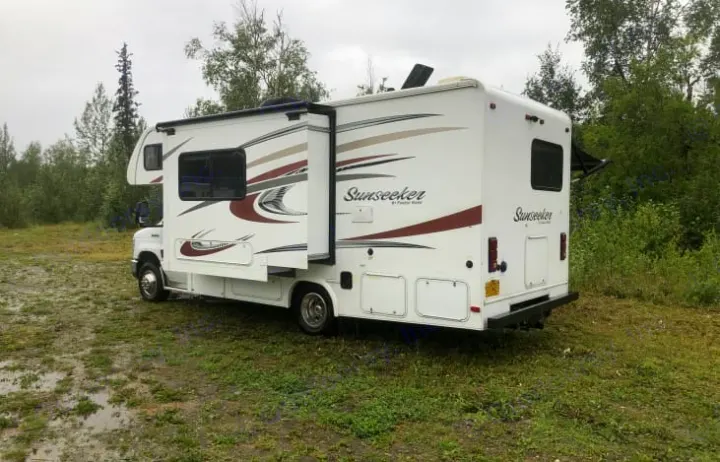 White Sunseeker RV rental parked on muddy grass, with its slide-out extended, ready for adventure.. Forest River Sunseeker 2016
