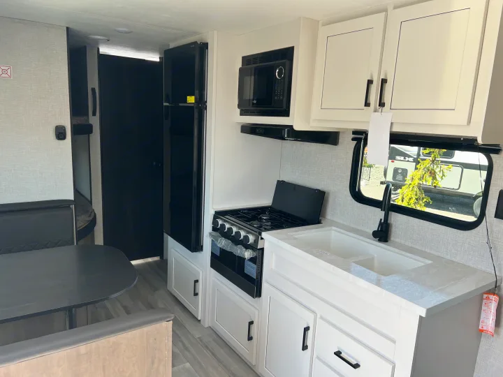 Spacious RV rental kitchen featuring a modern stove, microwave, fridge, and dinette. Clean interior.. Jayco Jay Flight SLX 2024