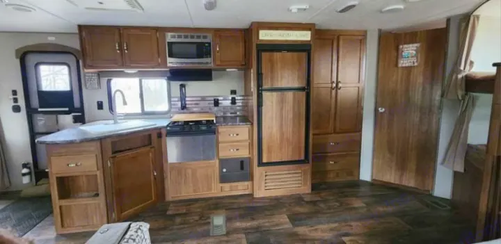 Explore this RV rental's cozy kitchen and living area, complete with wood-look flooring, ample storage, and appliances.. Keystone RV Springdale 2017