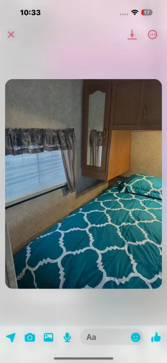RV rental bedroom: a cozy space with a teal patterned bed, window with blinds, and wood cabinets.. Keystone RV Cougar 2006