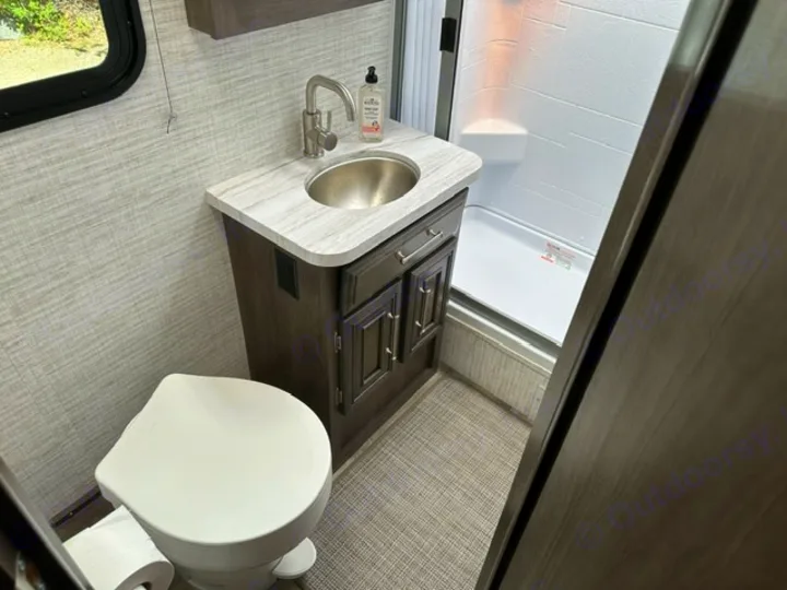 RV rental compact bathroom: white toilet, dark vanity with sink, and shower stall. Ready for your travels.. Entegra Coach Odyssey SE 22C 2024