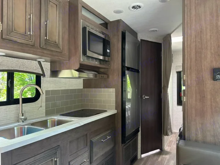 RV rental's modern kitchen: full-size fridge, sink, stove, microwave, and cabinetry. Perfect for your mobile adventures.. Entegra Coach Odyssey SE 22C 2024