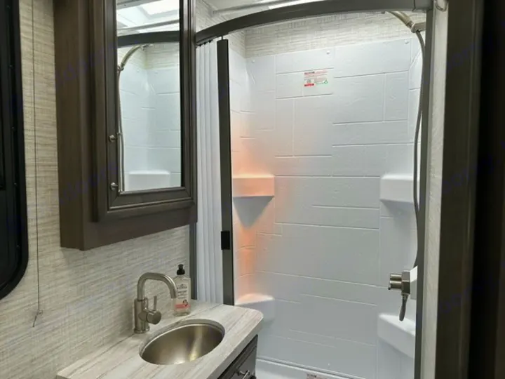 Compact RV rental bathroom with a sink, mirrored cabinet, and a white shower stall. Perfect for your travels.. Entegra Coach Odyssey SE 22C 2024
