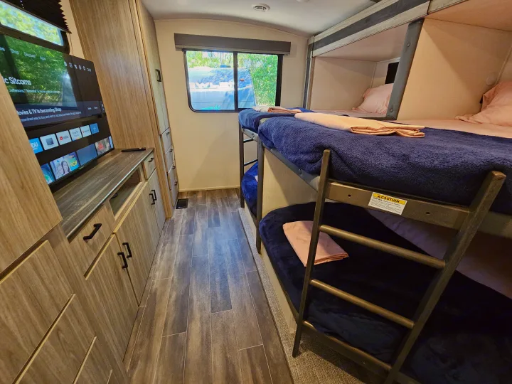 Cozy RV rental interior: bunk beds, entertainment center, and ample storage for a comfortable family trip.. Keystone Passport 2022