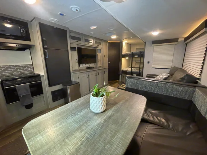 Modern rv rental interior with full kitchen, living area with comfortable seating and table, plus bunk beds.. Heartland RVs Mallard 2021