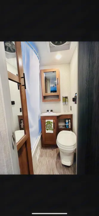 Compact RV rental bathroom features toilet, sink, shower, wood vanity, and fun camping towel. Ready for your adventures!. No Boundaries 19.8 2021