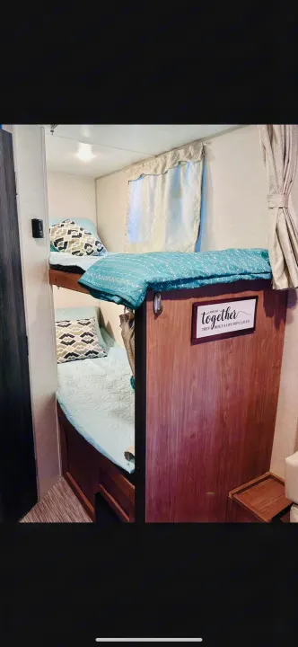 Cozy RV rental interior showing bunk beds with light blue bedding and patterned pillows. A welcoming sleep area.. No Boundaries 19.8 2021
