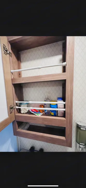 RV rental bathroom cabinet showing organized shelves with tension rods holding toiletries like toothpaste and bottles in place.. No Boundaries 19.8 2021