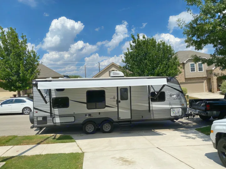 Jay Flight SLX travel trailer, perfect for an RV rental adventure, hooked to a truck on a sunny residential street.. Jayco Jay Flight SLX 2020