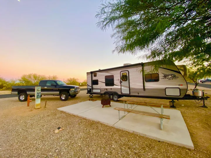 A travel trailer RV rental and truck parked at a tranquil campsite with a picnic table, fire pit, and beautiful sunset.. Jayco Jay Flight SLX 2020