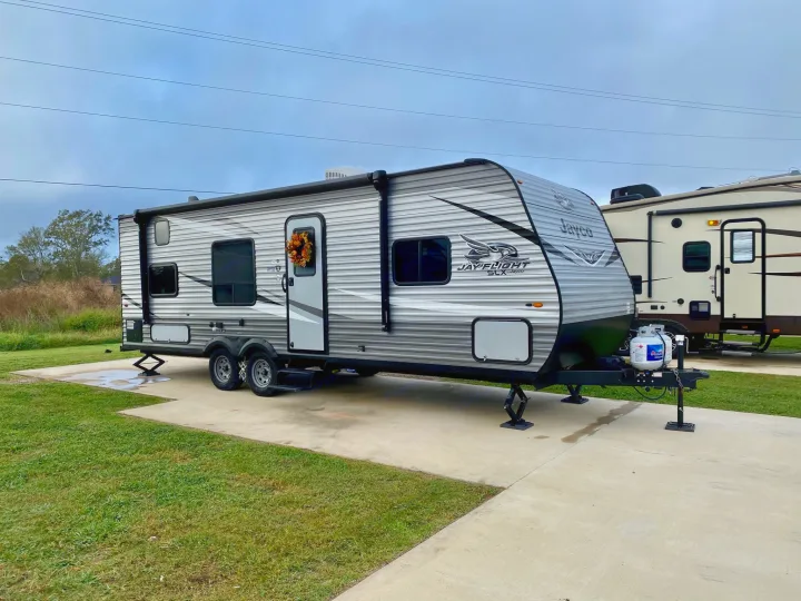 A modern Jayco travel trailer, ideal for an RV rental, parked on a concrete pad in an RV park for camping.. Jayco Jay Flight SLX 2020
