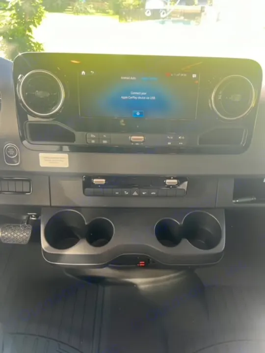 Inside an RV rental: modern dashboard with a bright infotainment screen, USB ports, climate controls, and cup holders.. Entegra Coach Qwest 24L 2024