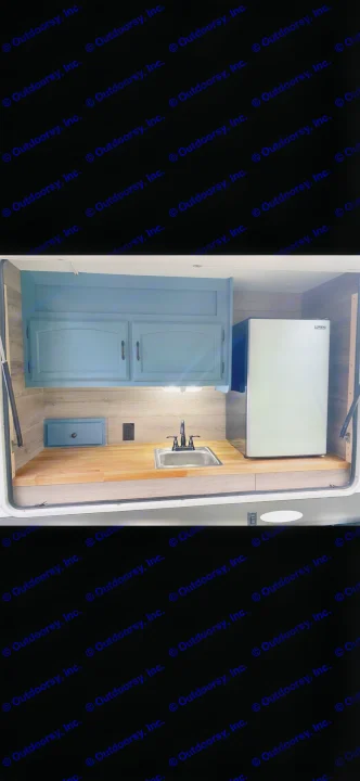 This RV rental offers an outdoor kitchen with blue cabinets, a sink, mini-fridge, and wood-look counters for convenient camping.. Forest River Wildwood 2012