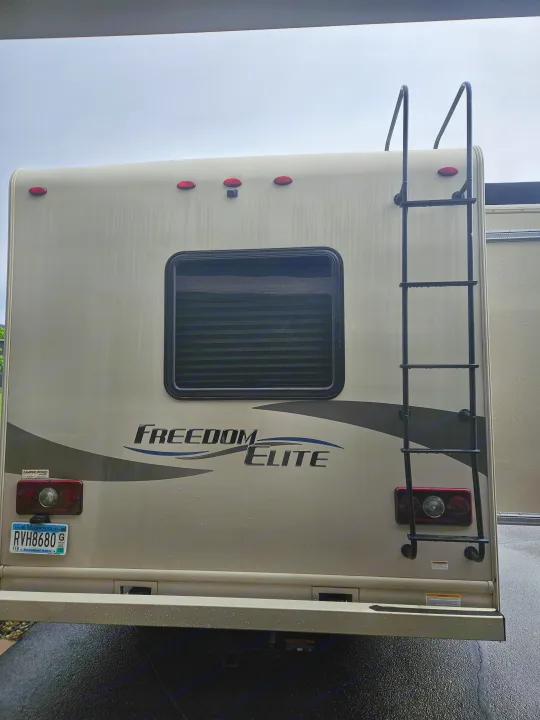 Rear of a tan Freedom Elite motorhome. Features a ladder, window, and MN license plate. Great for rv rental.. Thor Freedom Elite 2018