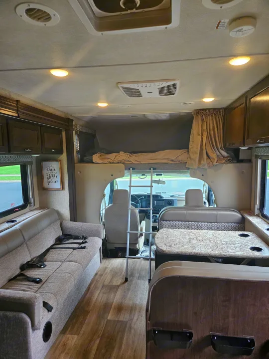 Clean, modern RV rental interior with a spacious living area, overhead bunk bed, comfortable sofa, and dinette.. Thor Freedom Elite 2018