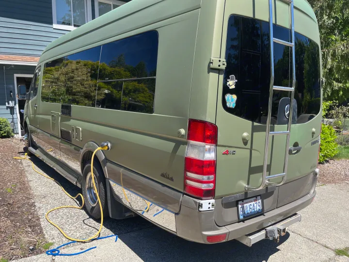 Green Sprinter RV rental van, plugged in via yellow cord at home, with ladder on back.. Other Other 2012