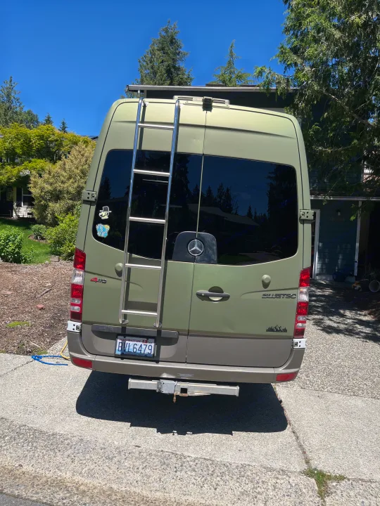 Rear view of an olive green Mercedes-Benz camper van with a ladder & hitch, ready for your next RV rental adventure.. Other Other 2012