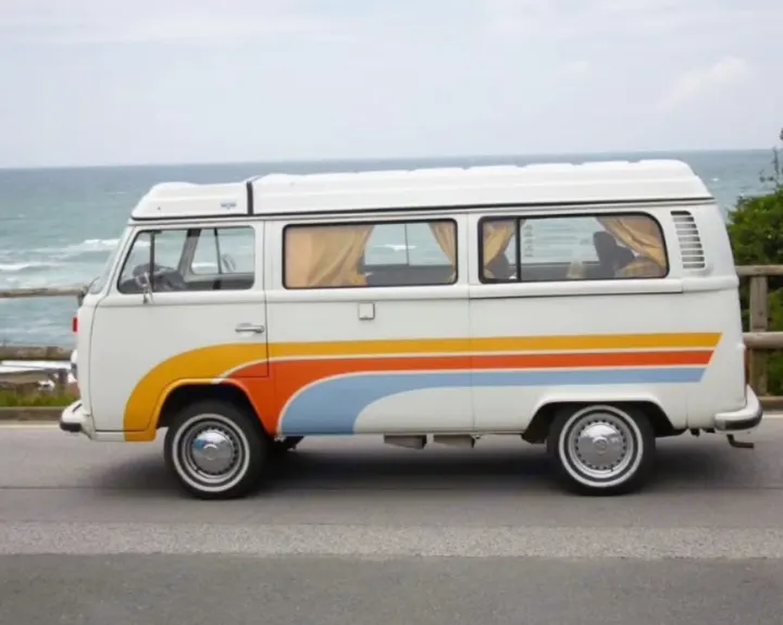 Classic VW camper van, perfect for an RV rental adventure, parked by the sea with colorful stripes.. Volkswagen T2 1978