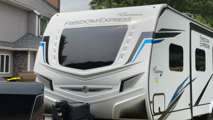 A sleek white Coachmen Freedom Express travel trailer, ideal for an rv rental, ready for camping adventures.. Coachmen 292BHDS FREEDOM EXPRESS LIBERTY EDITION 2022