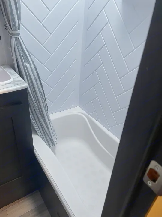 RV rental: Clean & modern bathroom with a tub/shower combo, white herringbone walls, and a tied-back striped curtain.. Coachmen 292BHDS FREEDOM EXPRESS LIBERTY EDITION 2022
