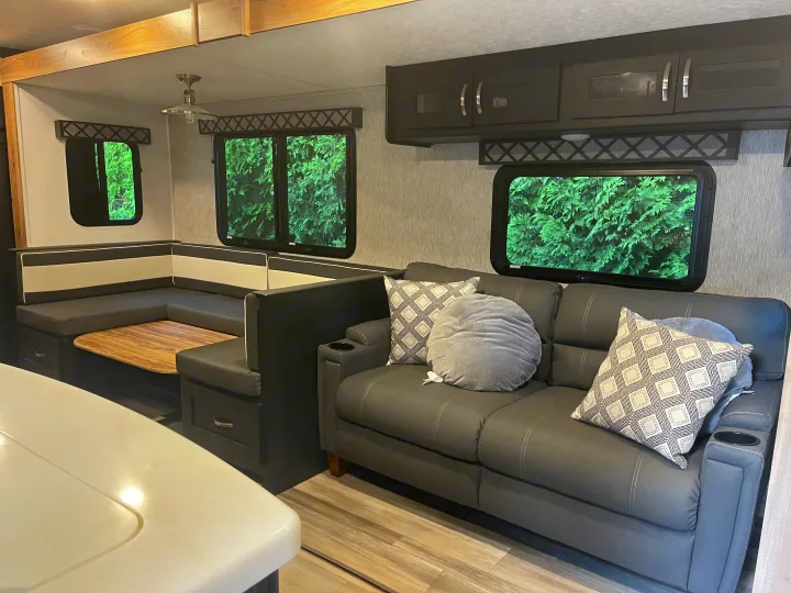 Comfortable RV rental interior featuring a spacious dinette, cozy couch, and ample overhead storage for your travels.. Coachmen 292BHDS FREEDOM EXPRESS LIBERTY EDITION 2022
