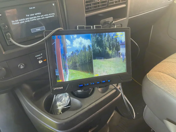 Inside an RV rental: a monitor displays multi-angle camera views, with a dashboard safety screen above.. Forest River Sunseeker LE 2023
