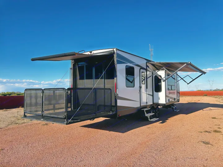 Spacious RV rental with extended awning & patio setup on gravel, ideal for outdoor living under clear skies.. Grand Design Momentum 2020