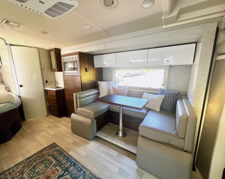 **RV rental** interior with a modern dining booth, kitchenette, and sleek overhead cabinets. Cozy and functional for travel.. Winnebago View 2022