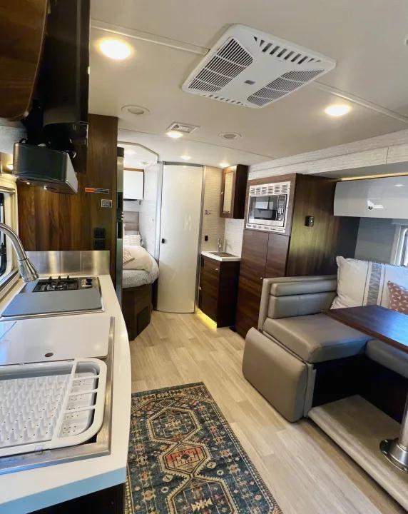 Spacious RV rental interior showcasing a modern kitchen, comfortable dining lounge, and glimpse of the bedroom.. Winnebago View 2022