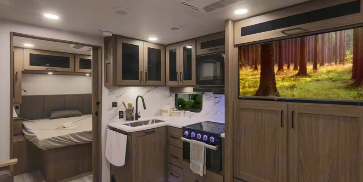 Modern RV rental interior featuring a cozy bedroom, full kitchen, and large screen showcasing a forest view.. Alliance Delta 251BH 2024