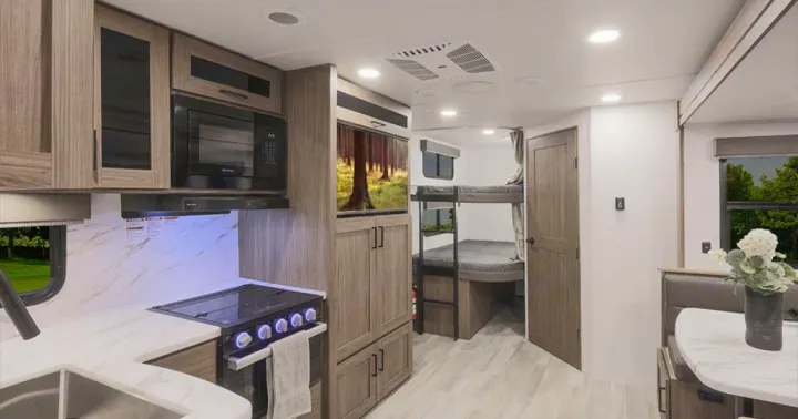 Modern RV rental interior showcasing a well-equipped kitchen, dining booth, entertainment, and bunk beds.. Alliance Delta 251BH 2024