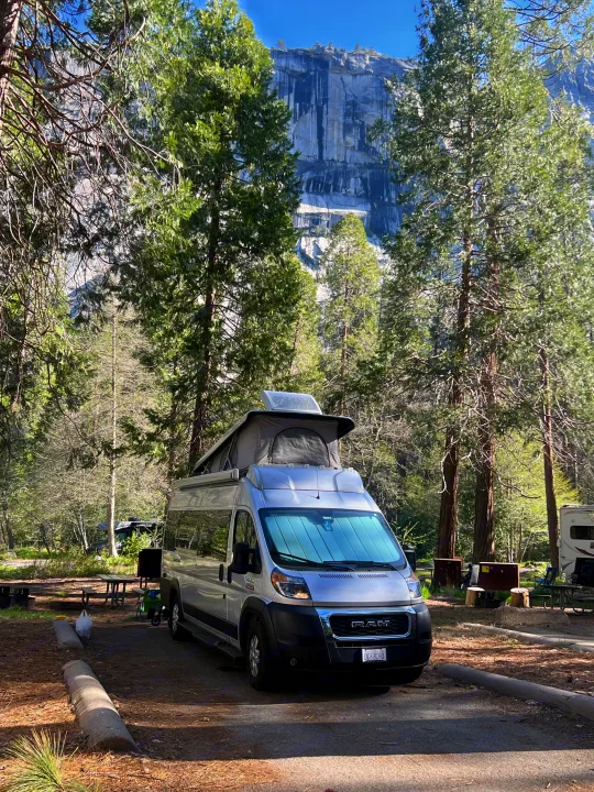 Silver camper van with pop-top at a scenic mountain campsite, ideal for an rv rental adventure.. Thor Motor Coach Sequence 2022
