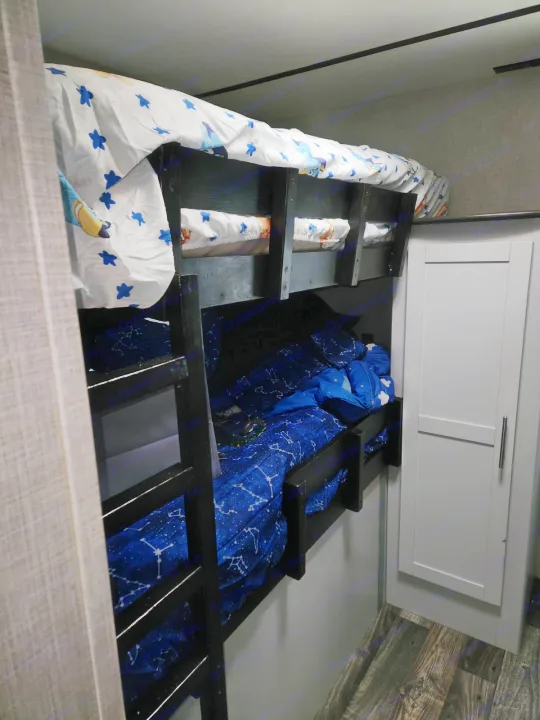 RV rental bunk beds: Cartoon sheets on top, constellation bedding below. A cozy, compact sleeping area with a wardrobe.. Keystone RV Bullet Ultra Lite 2020