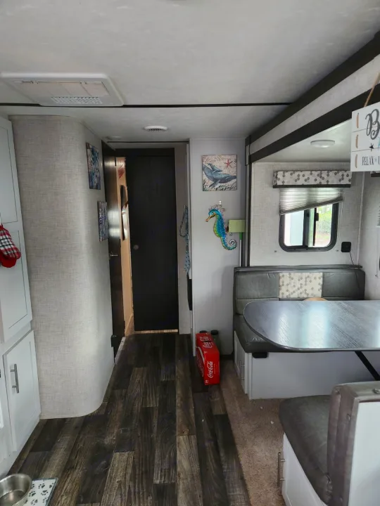 RV rental: interior view showing a gray dining booth, light wood-look floor, and coastal wall art.. Keystone RV Bullet Ultra Lite 2020