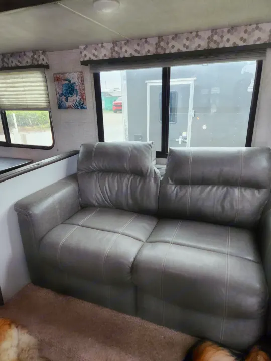 RV rental interior: comfy gray leather sofa, large windows, wall art, and a glimpse of pets.. Keystone RV Bullet Ultra Lite 2020