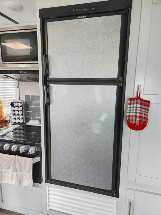 Compact RV rental kitchen showcasing a Dometic fridge, Furrion microwave, and stovetop.. Keystone RV Bullet Ultra Lite 2020
